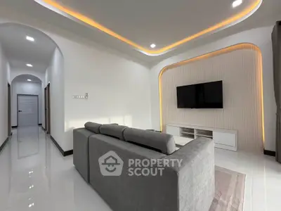 Modern living room with sleek design, featuring a gray sofa and wall-mounted TV.