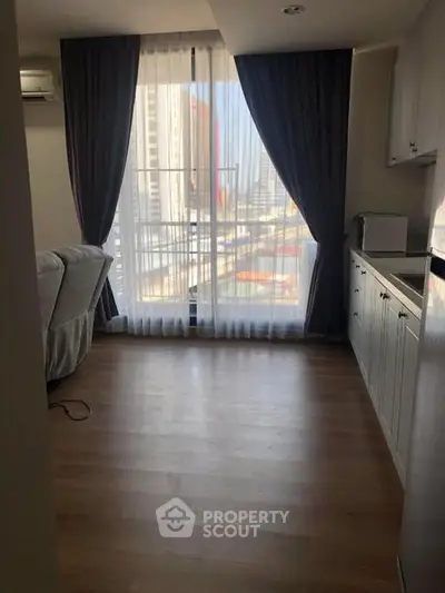 Modern living room with large window and city view, featuring sleek wooden flooring and elegant curtains.