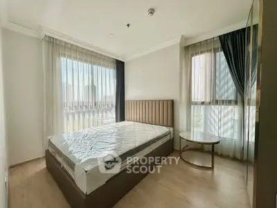 Spacious bedroom with large windows and modern furnishings in a bright apartment.
