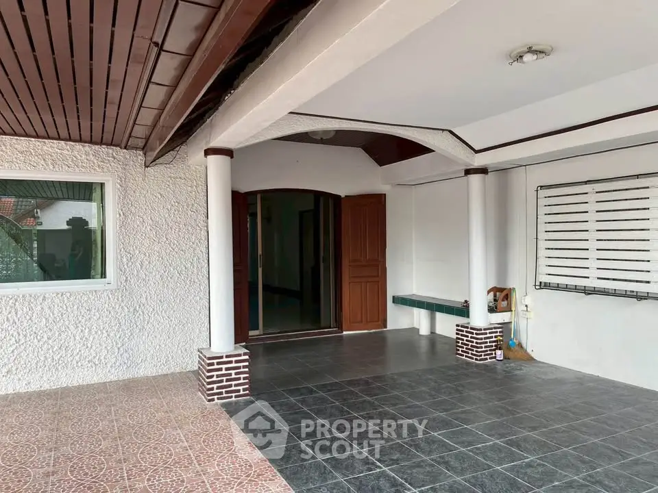 Spacious covered entrance with tiled flooring and elegant columns in a modern home.
