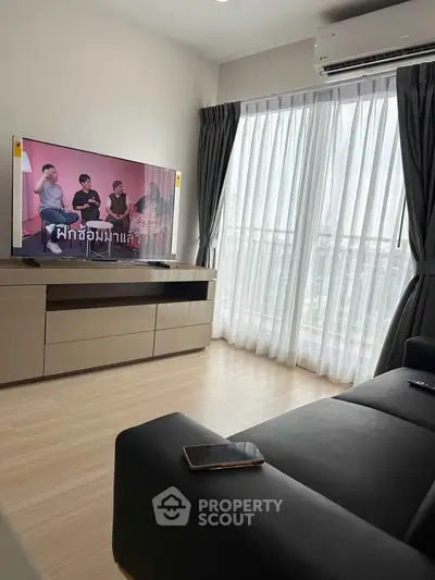 Modern living room with large window and sleek furniture, featuring a wall-mounted TV and air conditioning.