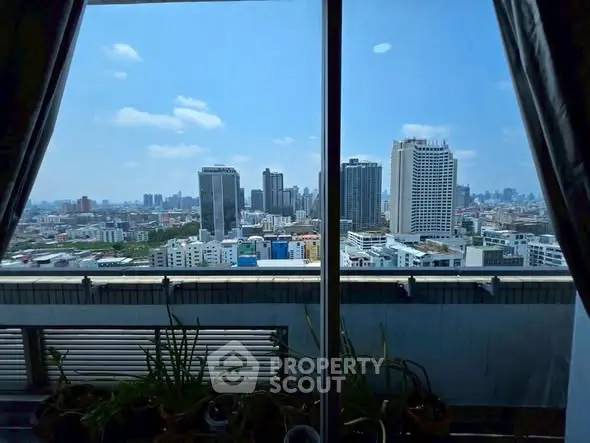 Stunning cityscape view from high-rise apartment window with clear blue sky.