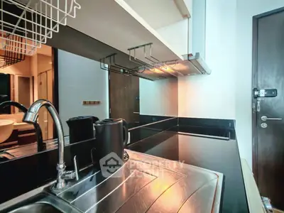 Modern kitchen with sleek black countertops and stainless steel sink, featuring a stylish open layout.