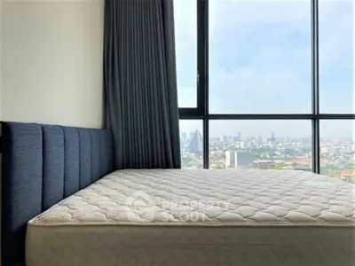 Spacious bedroom with city view and large window, featuring a comfortable mattress and elegant curtains.