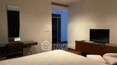 Spacious bedroom with modern furniture and TV, featuring a sleek dresser and cozy ambiance.