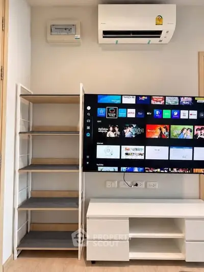 Modern living room with wall-mounted TV, air conditioning, and sleek shelving unit.