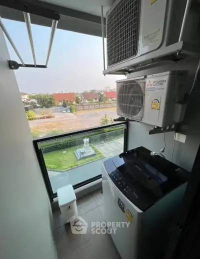 Compact laundry area with washing machine and scenic view from window.