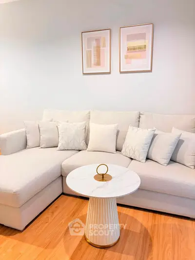 Elegant living room with modern white sectional sofa and stylish round coffee table on wooden floor.