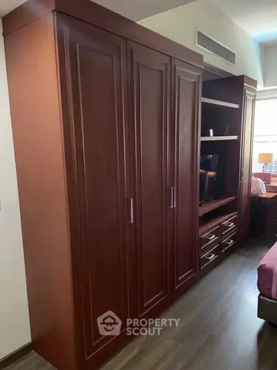 Spacious bedroom with elegant wooden wardrobe and modern TV unit