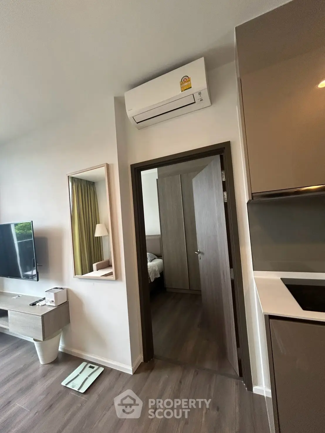 Modern apartment interior with sleek kitchen and cozy living area, featuring air conditioning and stylish decor.