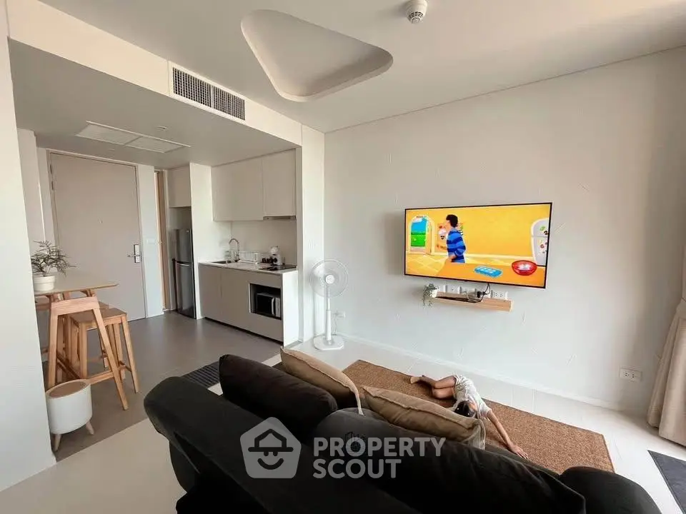 Modern living room with open kitchen, wall-mounted TV, and stylish decor in a contemporary apartment.