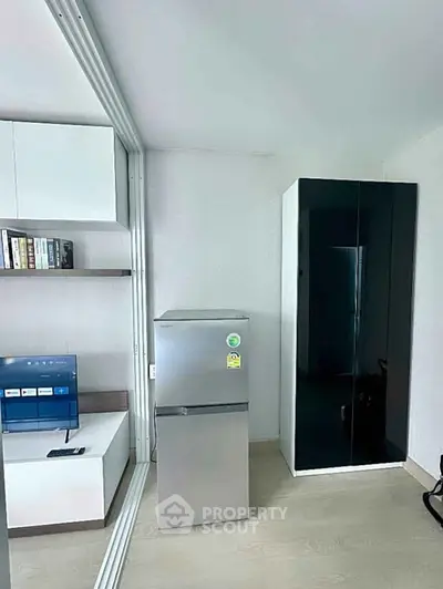 Modern apartment interior with sleek fridge and stylish storage solutions.