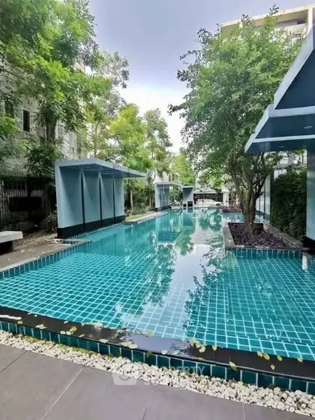 Luxurious outdoor swimming pool surrounded by lush greenery in a modern residential complex.