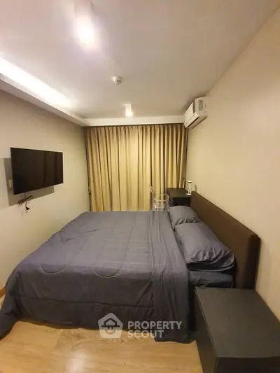 Cozy bedroom with modern furnishings and wall-mounted TV in a stylish apartment.