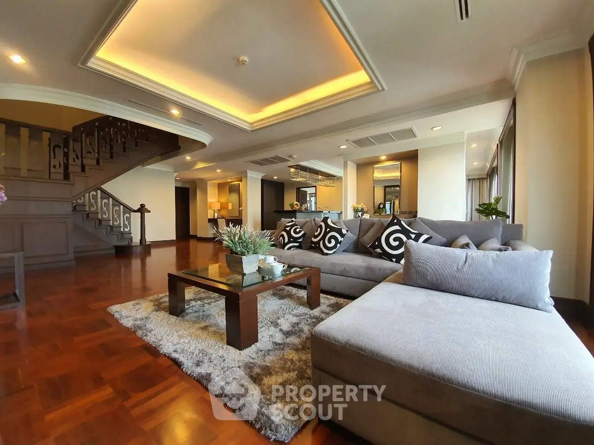 Luxurious open-plan living room with elegant staircase and plush seating area.