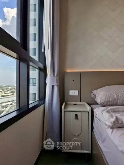 Modern bedroom with large window offering stunning city view, elegant bedside table, and luxurious bedding.