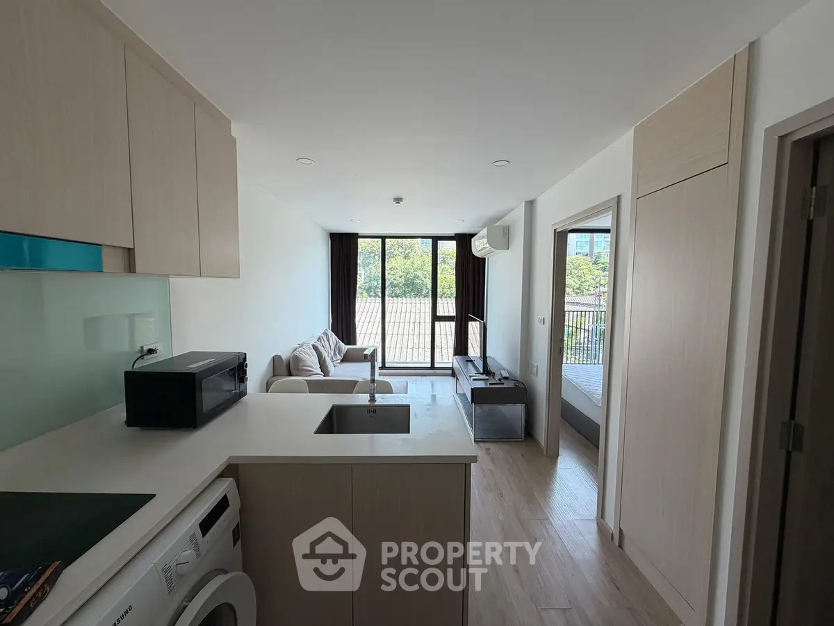 Modern open-plan living room with kitchen and balcony view in a stylish apartment.