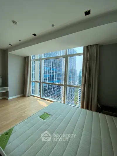 Spacious bedroom with floor-to-ceiling windows offering stunning city views in a modern high-rise.
