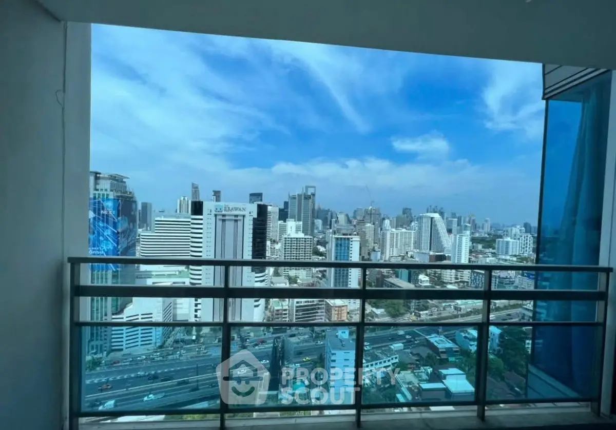 Stunning cityscape view from a high-rise balcony with clear blue skies.