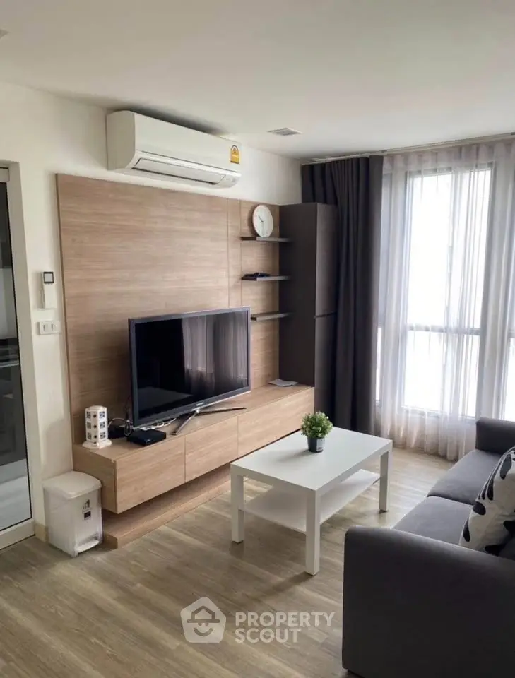 Modern living room with sleek wooden paneling, large TV, and natural light from tall windows.