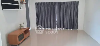 Spacious empty living room with sleek tiled flooring and large window draped with elegant curtains.
