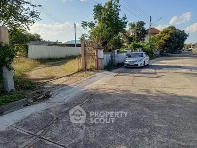 Spacious residential street with parked car and lush greenery, ideal for serene living.