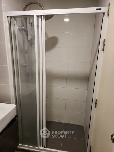 Compact bathroom shower area with sliding glass door and modern fixtures.
