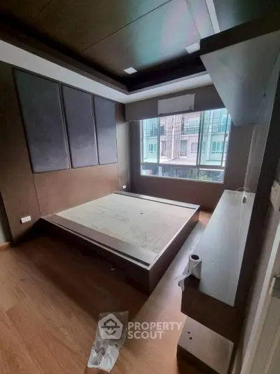 Modern bedroom with large window and sleek wooden flooring