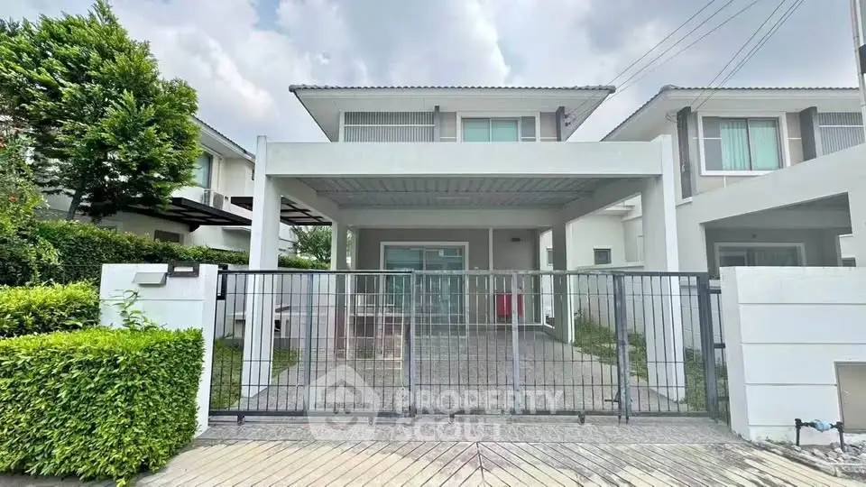 Modern two-story house with gated driveway and lush greenery