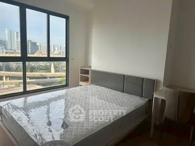 Modern bedroom with large window offering stunning city view, featuring a comfortable bed and sleek furnishings.