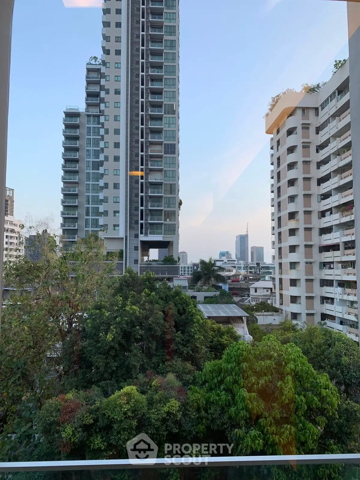 Stunning urban view from a high-rise apartment showcasing lush greenery and modern architecture.