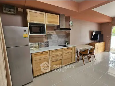Modern kitchen with wooden cabinets and dining area in open layout apartment.
