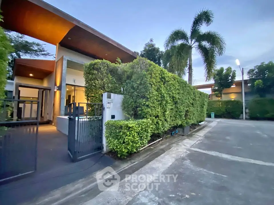 Modern villa exterior with lush greenery and sleek design in a serene neighborhood.