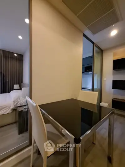 Modern apartment interior with glass dining table and cozy bedroom view