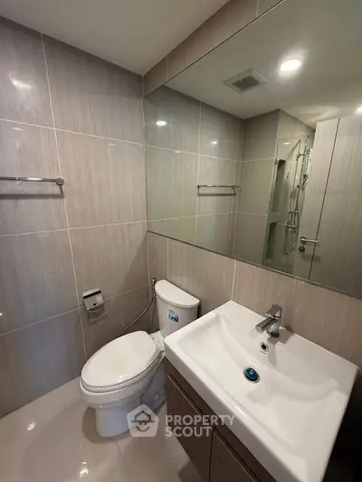 Modern bathroom with sleek fixtures and large mirror in a contemporary apartment.