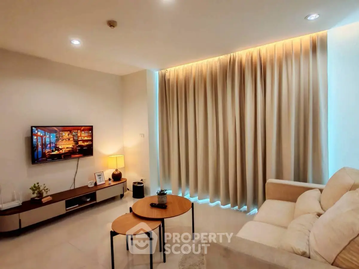 Modern living room with cozy sofa, wall-mounted TV, and elegant lighting.