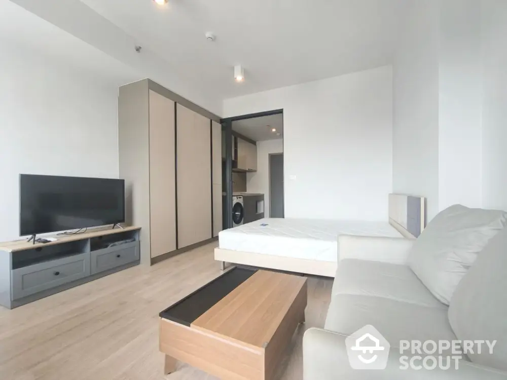 Modern studio apartment with open layout, featuring a cozy living area and sleek kitchen.