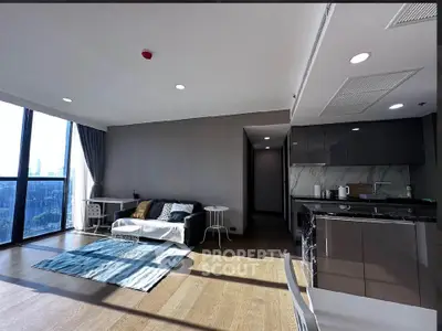 Modern living room with open kitchen and large windows offering city views.