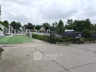 Spacious outdoor area with lush greenery and paved pathways, ideal for relaxation and leisure activities.