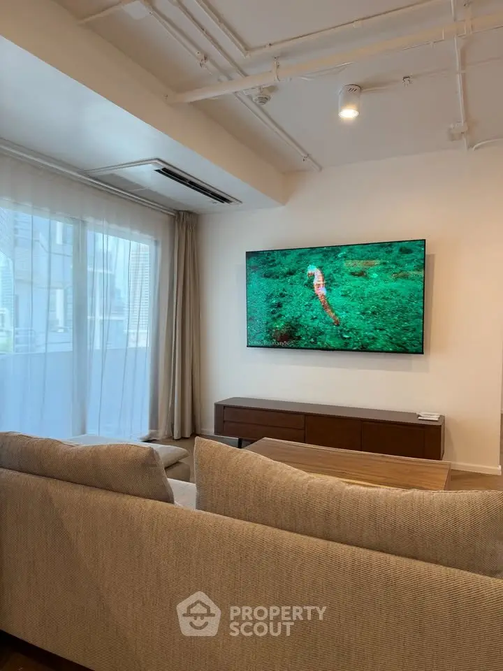 Modern living room with large TV and comfortable seating in a stylish apartment.