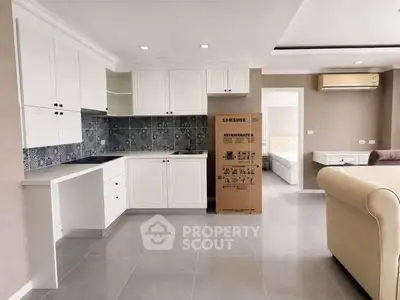 Modern kitchen with white cabinets and tiled backsplash in open layout apartment.