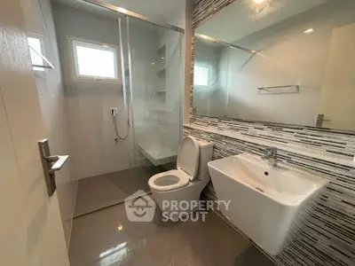 Modern bathroom with sleek design, featuring a glass shower enclosure and stylish sink.