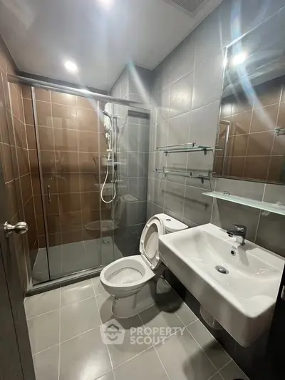 Modern bathroom with glass shower enclosure and sleek fixtures in a contemporary apartment.