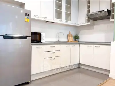 Modern kitchen with sleek white cabinets and stainless steel appliances in a stylish corner layout.