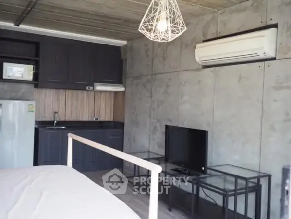 Modern industrial-style studio apartment with concrete walls and sleek furnishings.