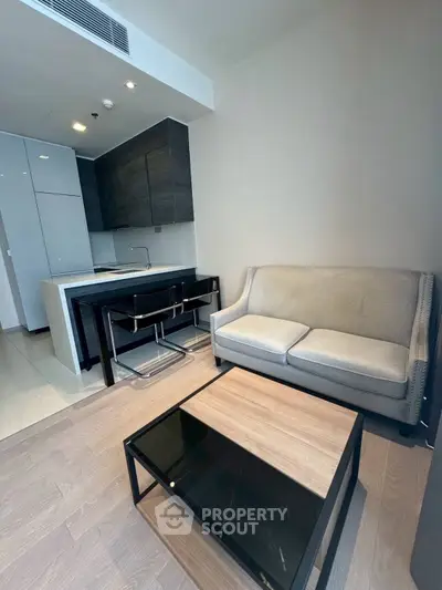 Modern living room with sleek kitchen and cozy seating area in contemporary apartment.