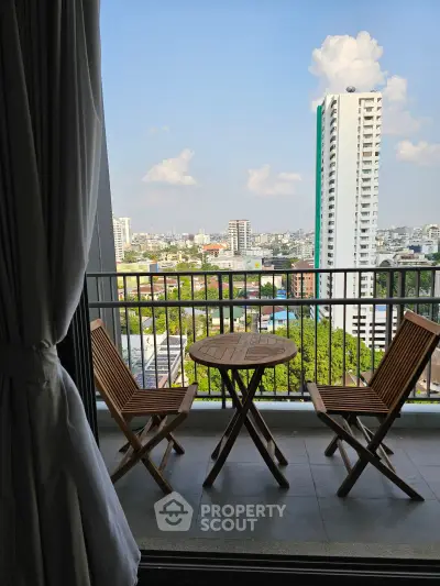 Stunning city view from a high-rise balcony with wooden furniture, perfect for relaxation.