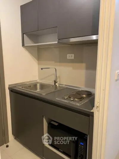 Compact modern kitchen with sleek cabinetry and built-in appliances in a cozy apartment.