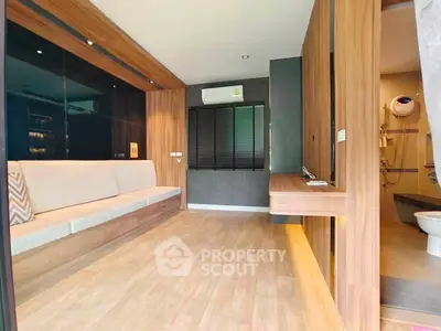 Modern living room with wooden accents and built-in seating, adjacent to a stylish bathroom.