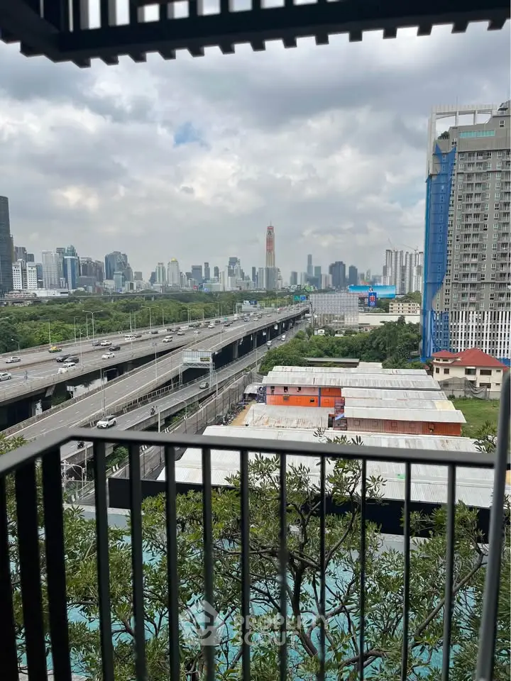 Stunning cityscape view from a high-rise balcony overlooking urban skyline and highway.